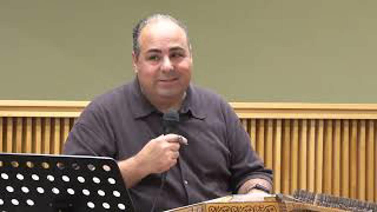 Man sitting down and holding a microphone. 